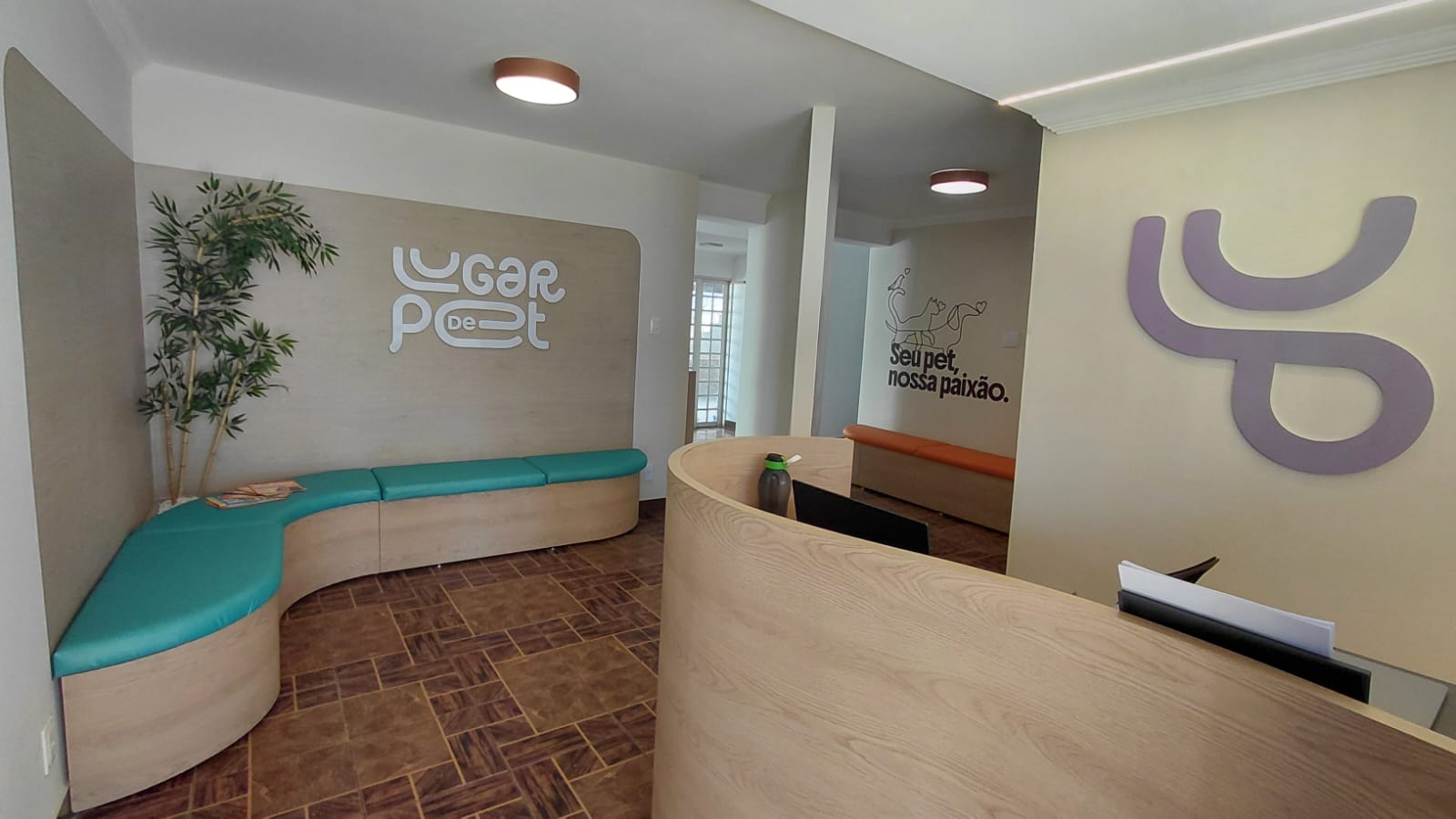 Fachada da Clínica, a clínica é uma casa de esquina com muro de pedra e portão de pedrestre e carro em grade branca. Em destaque aparece um letreiro luminoso com o nome da clínica: Lugar de Pet