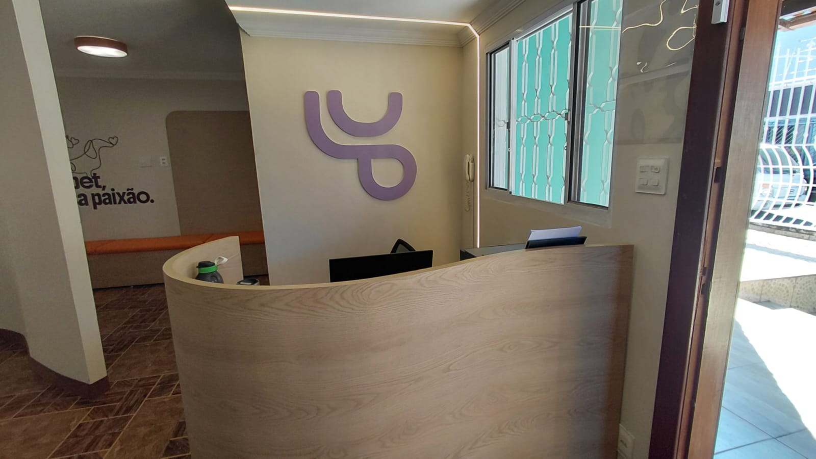 Recepção Lugar de Pet, aparece um balcão de atendimento com formato curvo e ao fundo o símbolo da marca